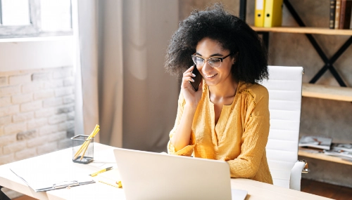 Happy woman on phone call while working at desk